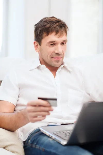 Hombre con portátil y tarjeta de crédito en casa —  Fotos de Stock