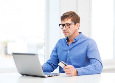 Man with laptop and credit card at home clipart