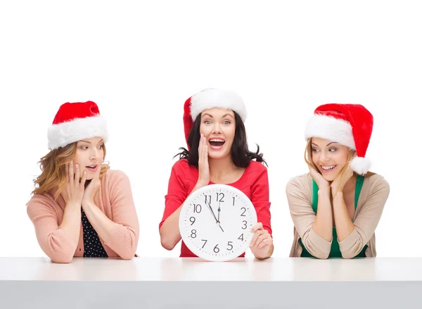 Women in santa helper hats with clock showing 12 — Stock Photo, Image