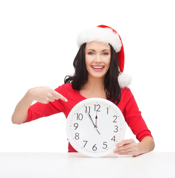 Femme en santa chapeau d'aide avec horloge montrant 12 — Photo