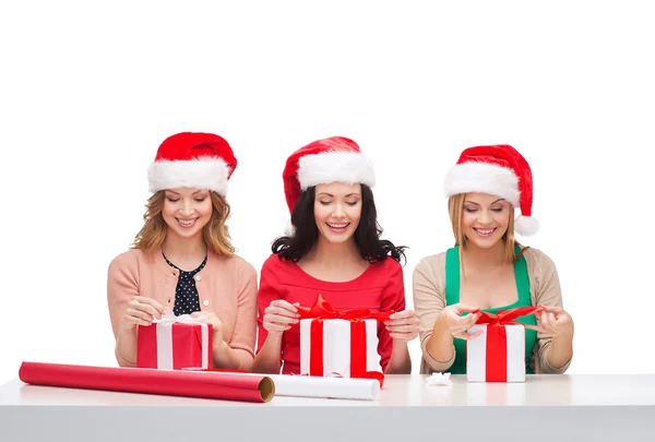 Donne sorridenti in cappelli di Babbo Natale con scatole regalo — Foto Stock