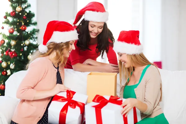 Frauen in Weihnachtsmannmützen mit vielen Geschenkschachteln Stockbild
