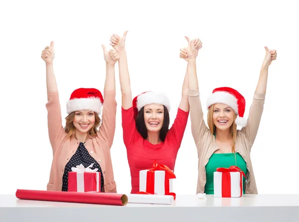 Donne sorridenti in cappelli di Babbo Natale con scatole regalo — Foto Stock