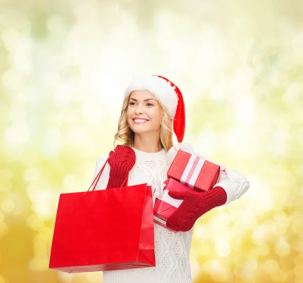 Vrouw in helper kerstmuts met shopping tassen — Stockfoto