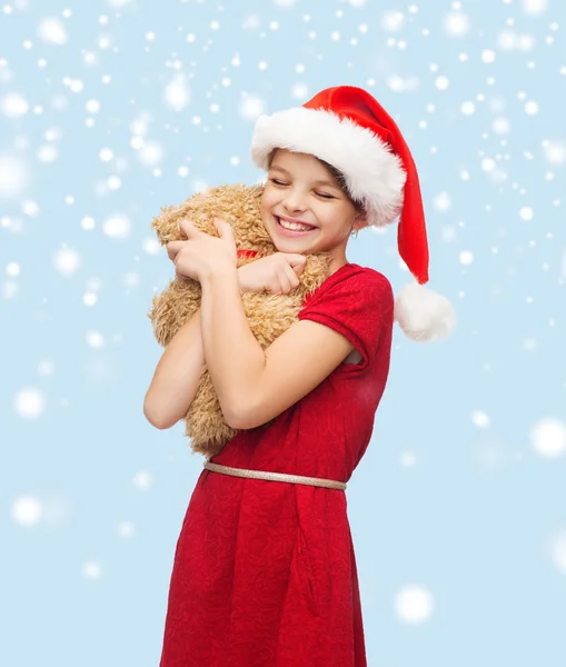 Lachende meisje in helper kerstmuts met teddy bear — Stockfoto