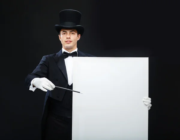 Magician in top hat with magic wand showing trick — Stock Photo, Image