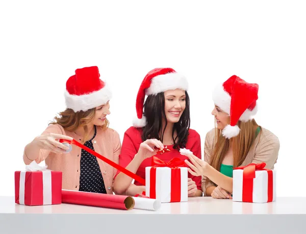Donne sorridenti in cappelli di Babbo Natale con scatole regalo — Foto Stock