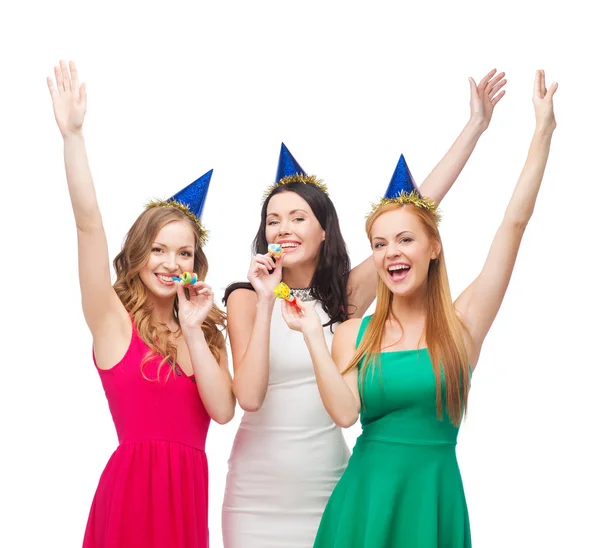 Tres mujeres sonrientes en sombreros soplando cuernos de favor —  Fotos de Stock