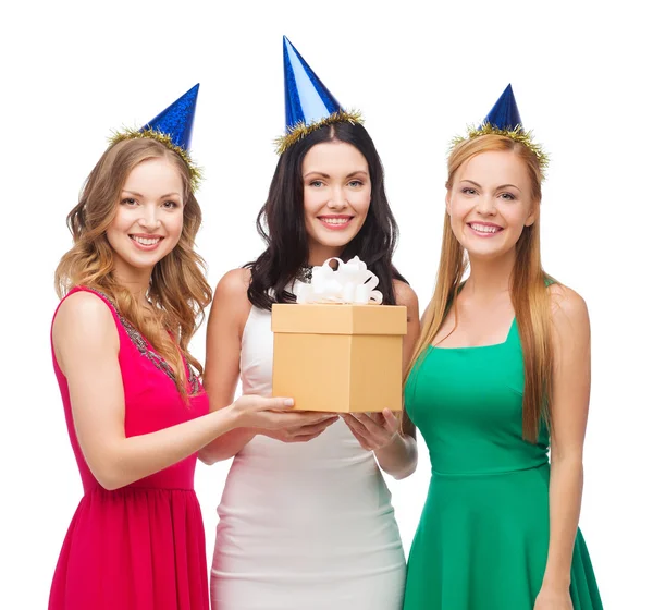 Tres mujeres sonrientes en sombreros azules con caja de regalo —  Fotos de Stock