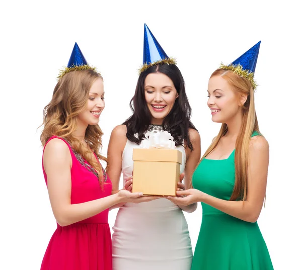 Tres mujeres sonrientes en sombreros azules con caja de regalo — Foto de Stock