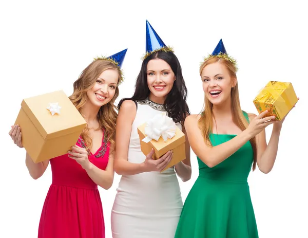 Tres mujeres sonrientes en sombreros azules con cajas de regalo — Foto de Stock