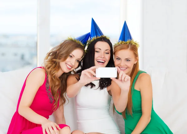 Three smiling women in hats having fun with camera Stock Photo