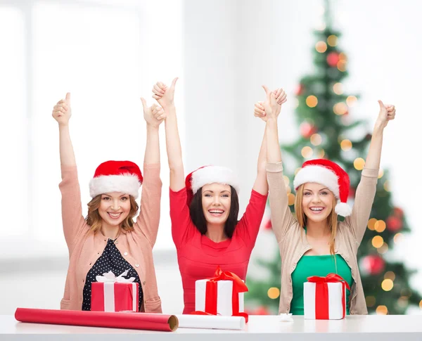 Mulheres sorridentes em santa helper chapéus com caixas de presente — Fotografia de Stock