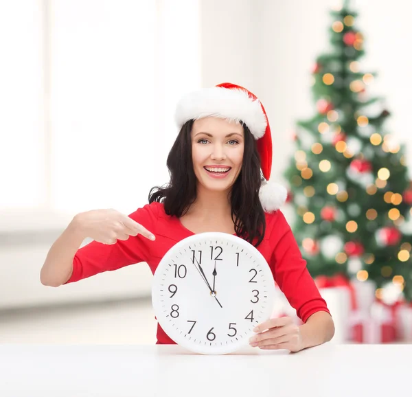 Femme en santa chapeau d'aide avec horloge montrant 12 — Photo