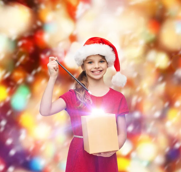 Chica sonriente en sombrero de ayudante de santa con caja de regalo — Foto de Stock
