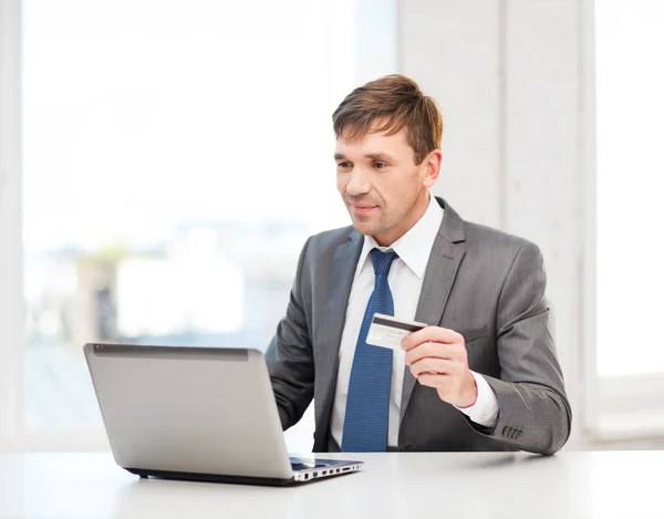 Homem com laptop e cartão de crédito no escritório — Fotografia de Stock