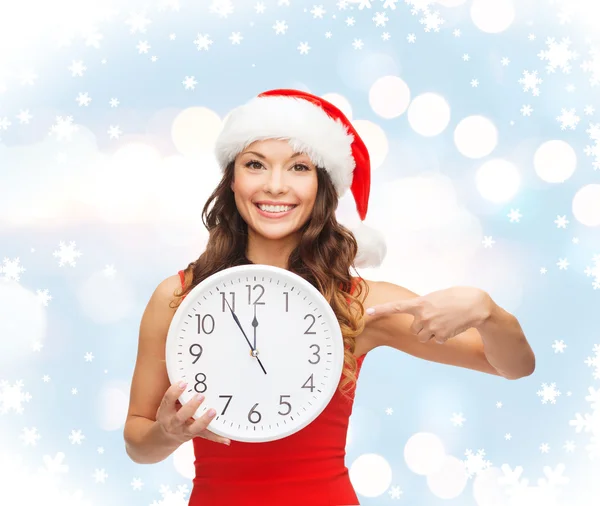 Femme en santa chapeau d'aide avec horloge montrant 12 — Photo