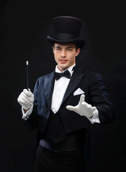 Magician in top hat with magic wand showing trick Stock Picture