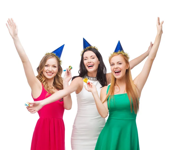 Tres mujeres sonrientes en sombreros soplando cuernos de favor —  Fotos de Stock