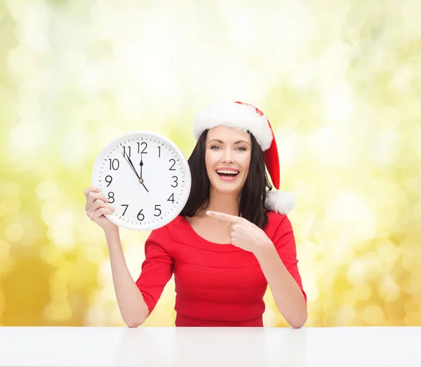 Femme en santa chapeau d'aide avec horloge montrant 12 — Photo