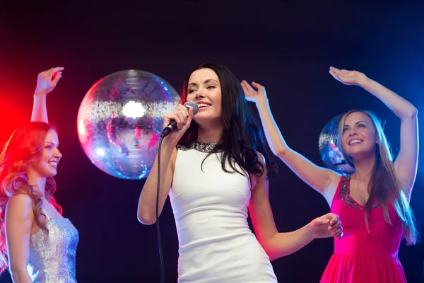 Tres mujeres sonrientes bailando y cantando karaoke — Foto de Stock