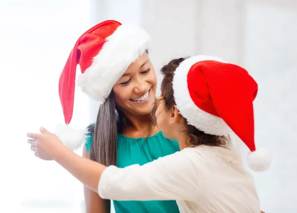 Hugging mother and daughter in santa helper hats — Stock Photo, Image