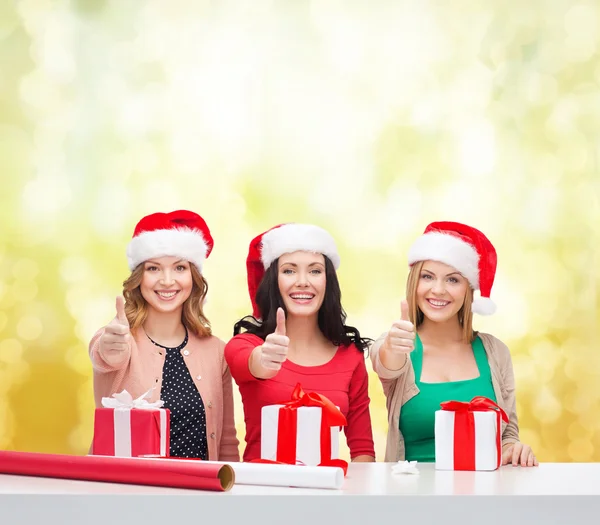 Mulheres sorridentes em santa helper chapéus com caixas de presente — Fotografia de Stock