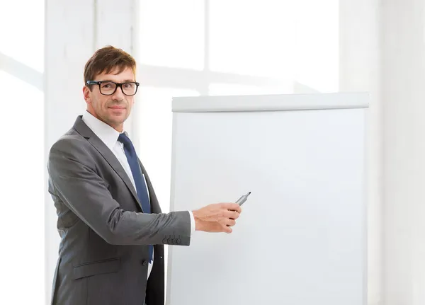 Businessman pointing to flip board in office — Stock Photo, Image