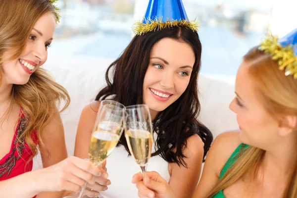 Tre kvinnor som bär hattar med champagneglas — Stockfoto