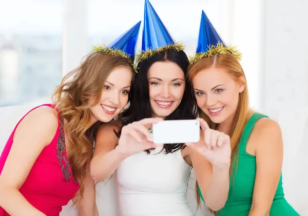 Three smiling women in hats having fun with camera Stock Picture