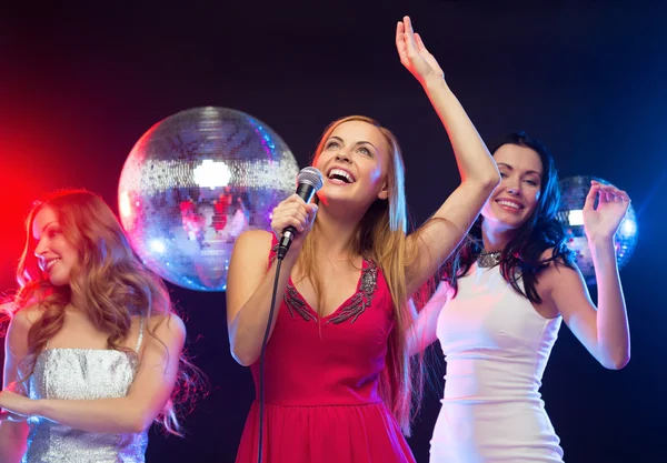 Tres mujeres sonrientes bailando y cantando karaoke — Foto de Stock