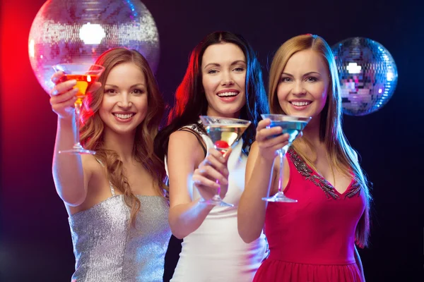 Drie glimlachende vrouwen met cocktails en disco bal — Stockfoto