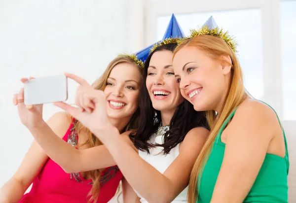 Drie lachende vrouwen in hoeden met plezier met camera — Stockfoto
