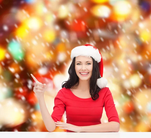 Mulher em Papai Noel chapéu auxiliar apontando para algo — Fotografia de Stock