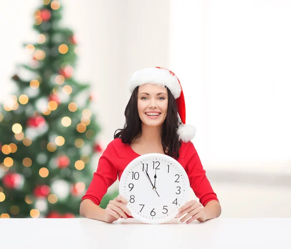 Mujer en sombrero de ayudante de santa con reloj que muestra 12 — Foto de Stock