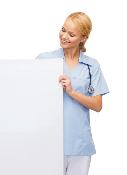 Smiling female doctor or nurse with blank board — Stockfoto