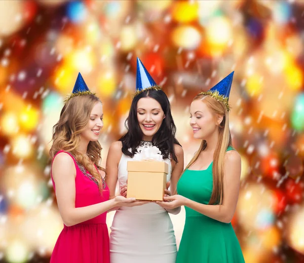 Tres mujeres sonrientes en sombreros azules con caja de regalo —  Fotos de Stock