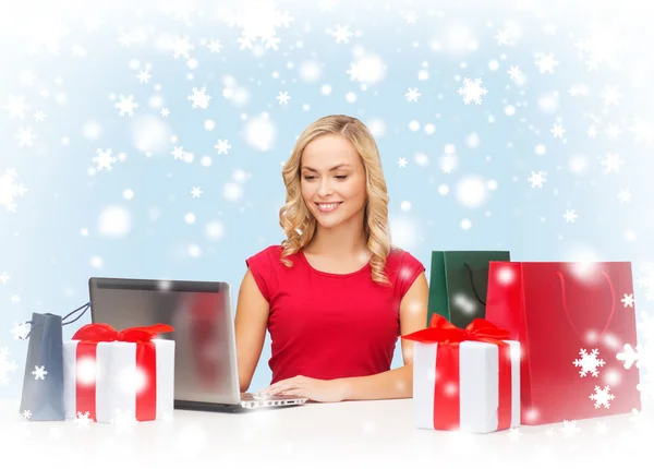 Woman with gift boxes, bags and laptop computer — Stock Photo, Image