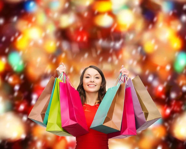 Mujer en vestido rojo con coloridas bolsas de compras — Foto de Stock