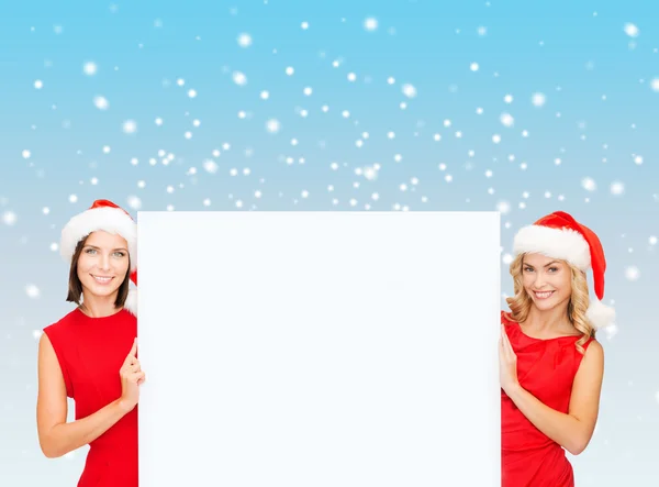 Frauen in Weihnachtsmannhelfermützen mit weißem Brett — Stockfoto