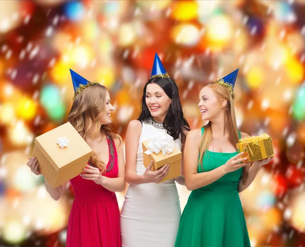 Tres mujeres sonrientes en sombreros azules con cajas de regalo — Foto de Stock