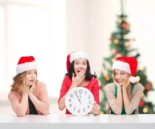 Mujeres en sombreros de Santa Helper con reloj que muestra 12 —  Fotos de Stock