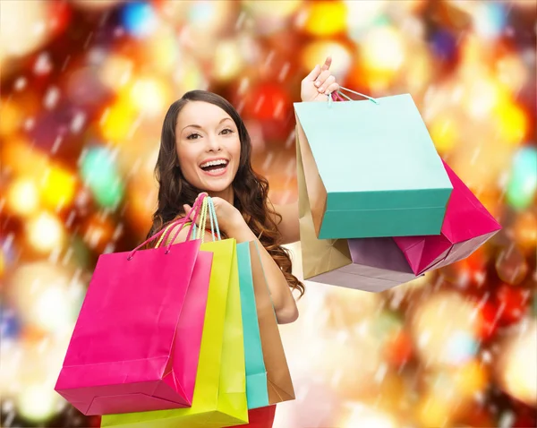 Mujer en vestido rojo con coloridas bolsas de compras —  Fotos de Stock