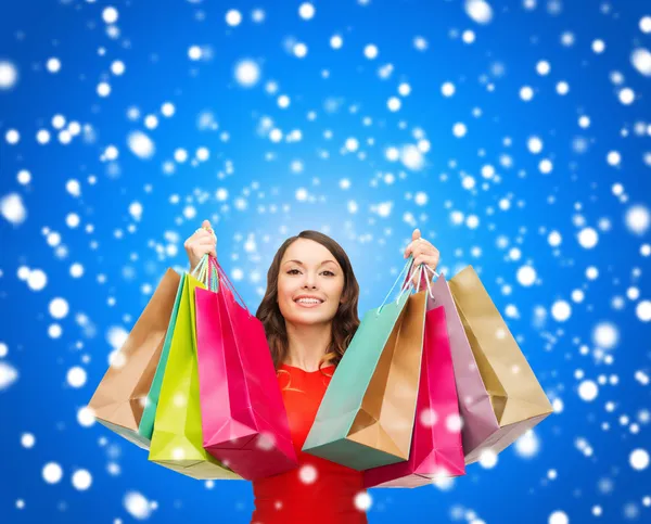 Vrouw in rode jurk met kleurrijke shopping tassen — Stockfoto