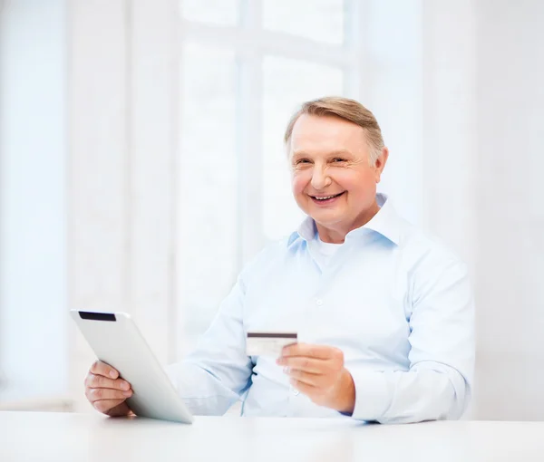 Old man with tablet pc and credit card at home — Stock Photo, Image