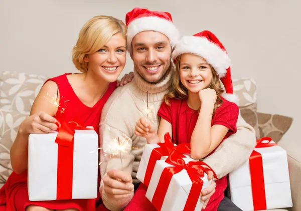 Familia sonriente sosteniendo cajas de regalo y destellos — Foto de Stock