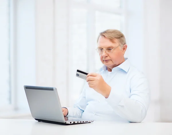 Gammal man med laptop och kreditkort hemma — Stockfoto