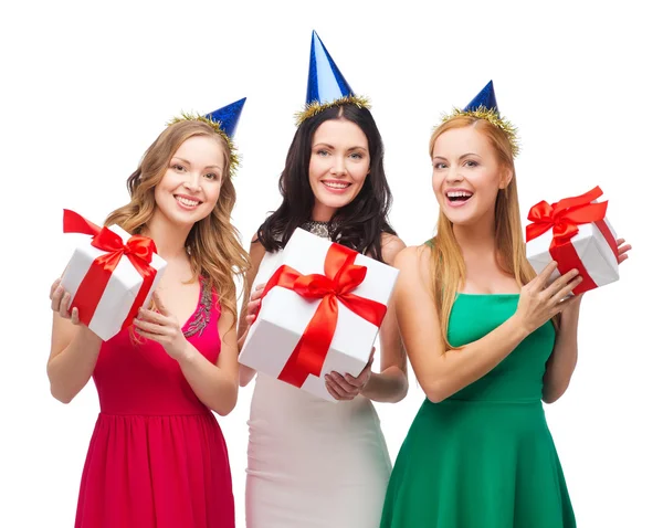 Três mulheres sorridentes em chapéus azuis com caixas de presente — Fotografia de Stock