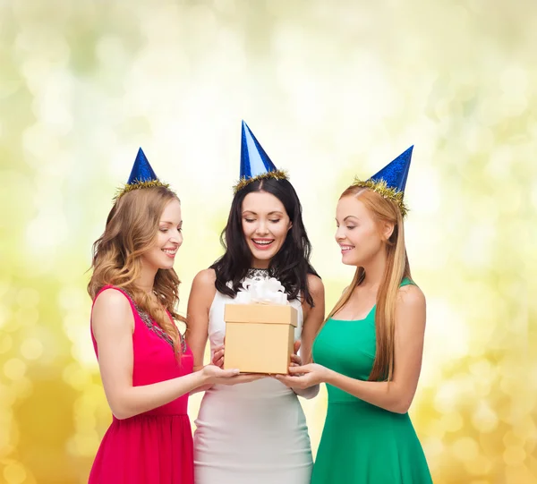 Tres mujeres sonrientes en sombreros azules con caja de regalo — Foto de Stock