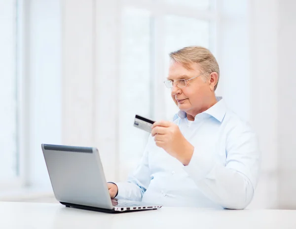 Gammal man med laptop och kreditkort hemma — Stockfoto